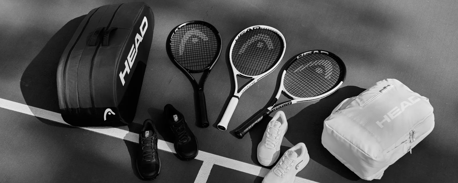 Tennistaschen, Schläger und Schuhe von HEAD auf einem Platz